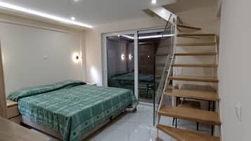 Een slaapkamer met een bed, een bureau, een stoel en een trap.