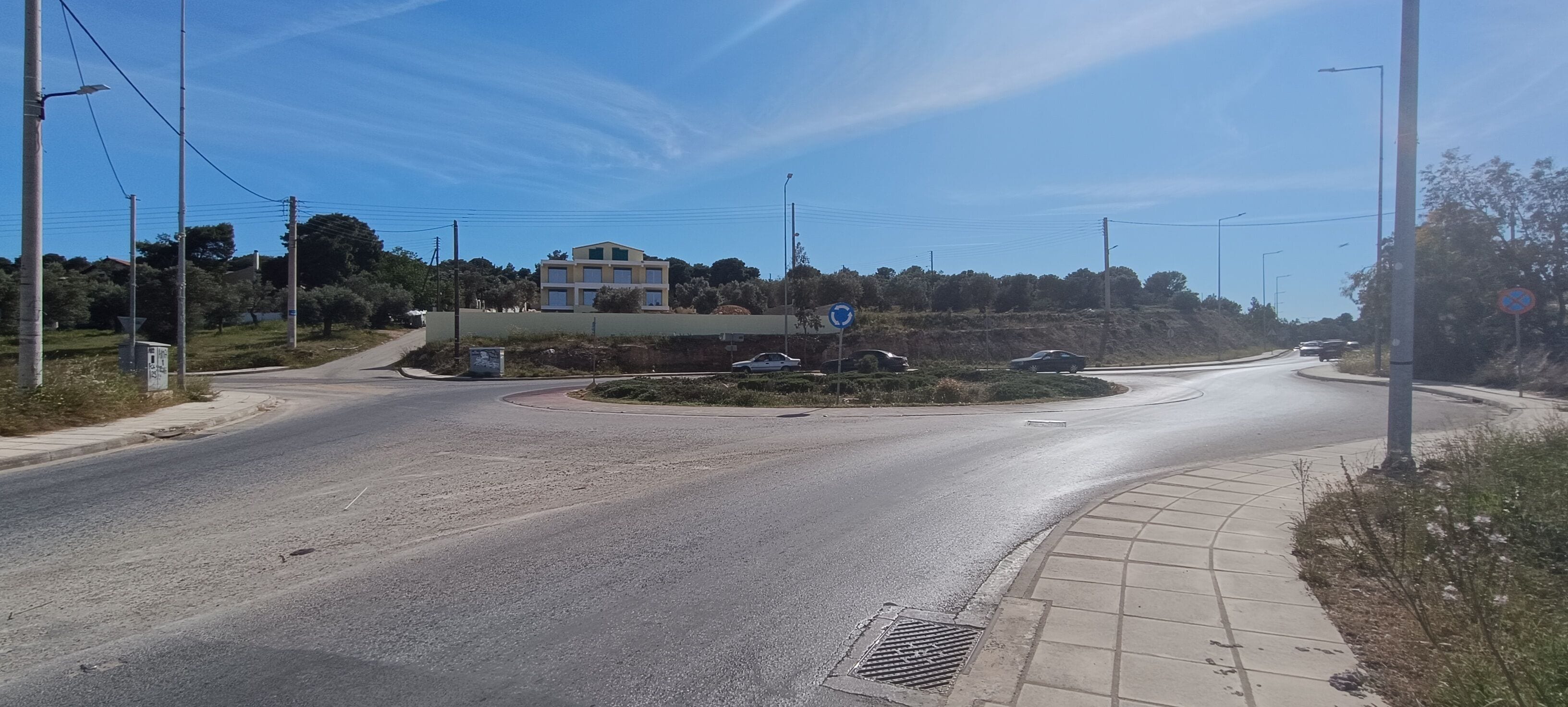 Una glorieta con una acera para peatones, un edificio al fondo y un cielo despejado.