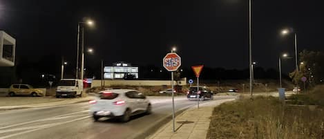 A nighttime street scene with cars, streetlights, and road signs.