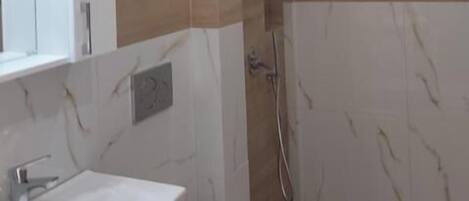 Un baño moderno con tocador de mármol, inodoro y zona de ducha.