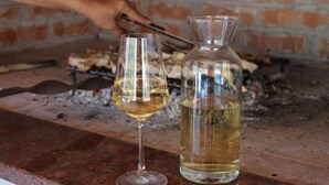 Una copa de vino blanco y una botella sobre una encimera.