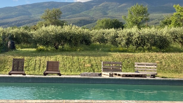 A pool with wooden loungers and a view of a mountainous landscape. - Maison de La Porte des Loups au Pied du Ventoux à Ste Colombe (Bédoin)