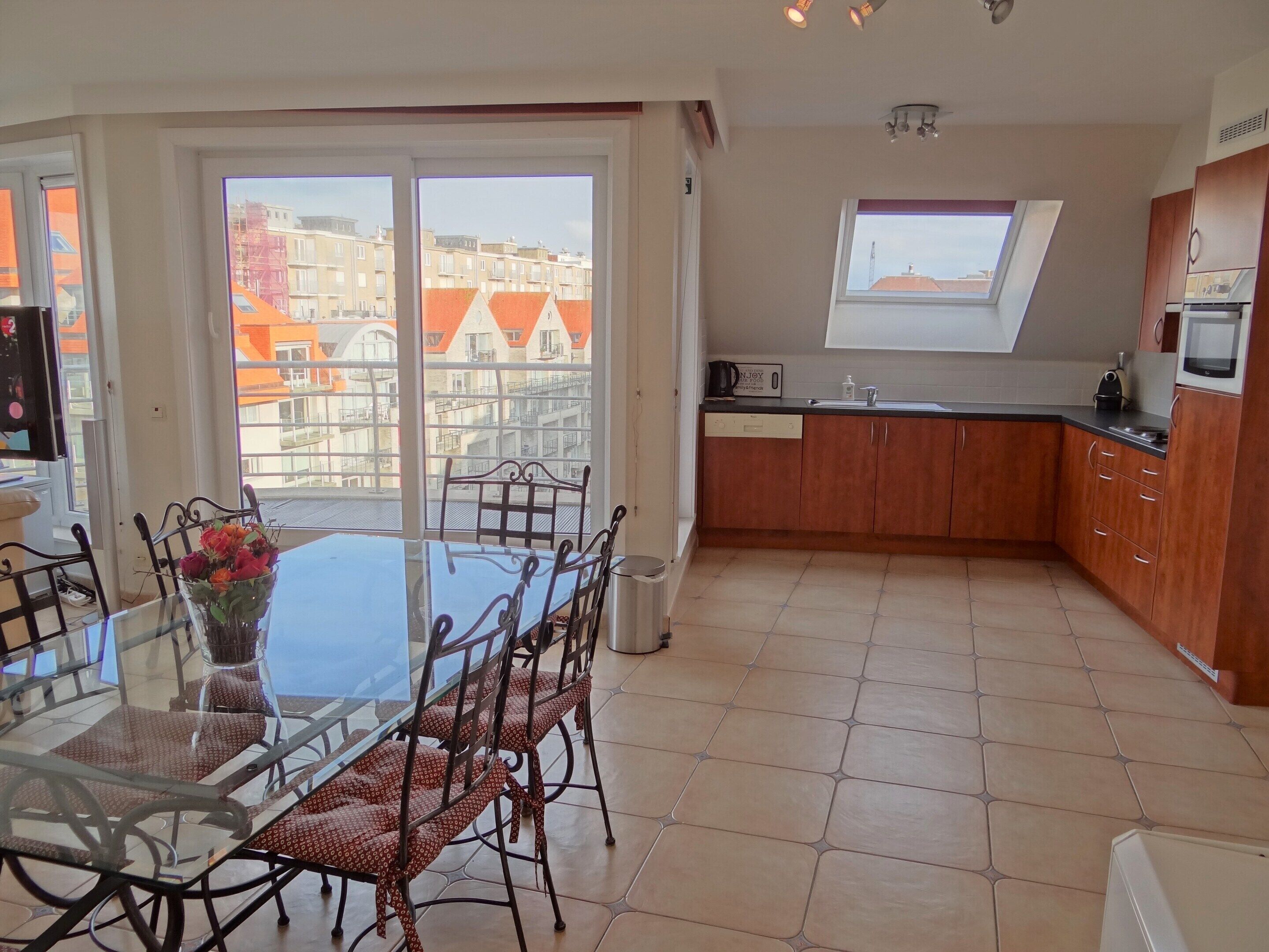 A modern kitchen with wooden cabinets, a black countertop, and a window overlooking a cityscape.