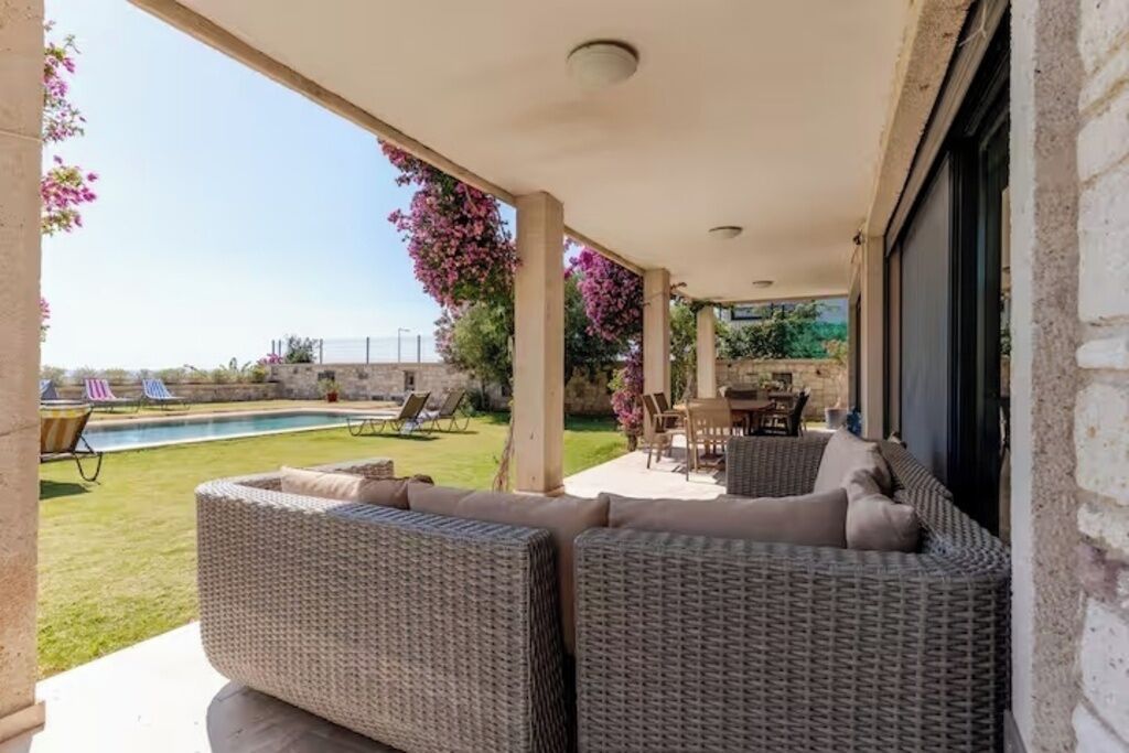 Un espace extérieur aménagé, abrité et doté de mobilier en osier, une piscine et une vue sur le paysage.