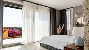 Un dormitorio moderno con una cama grande, una mesita de noche de madera, una lámpara y vistas a flores a través de una puerta corrediza.