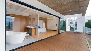 A modern bathroom with a freestanding bathtub, wooden flooring, and large glass doors leading to a balcony. - Villa O2 - beautiful property in Alcudia (Alcudia)