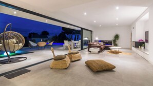 A modern living room with a large glass door leading to an outdoor area, wicker furniture, and a white sofa set. - Villa O2 - beautiful property in Alcudia (Alcudia)