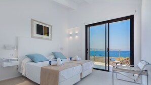 Ein modernes Schlafzimmer mit Bett, einer Bank und Meerblick.