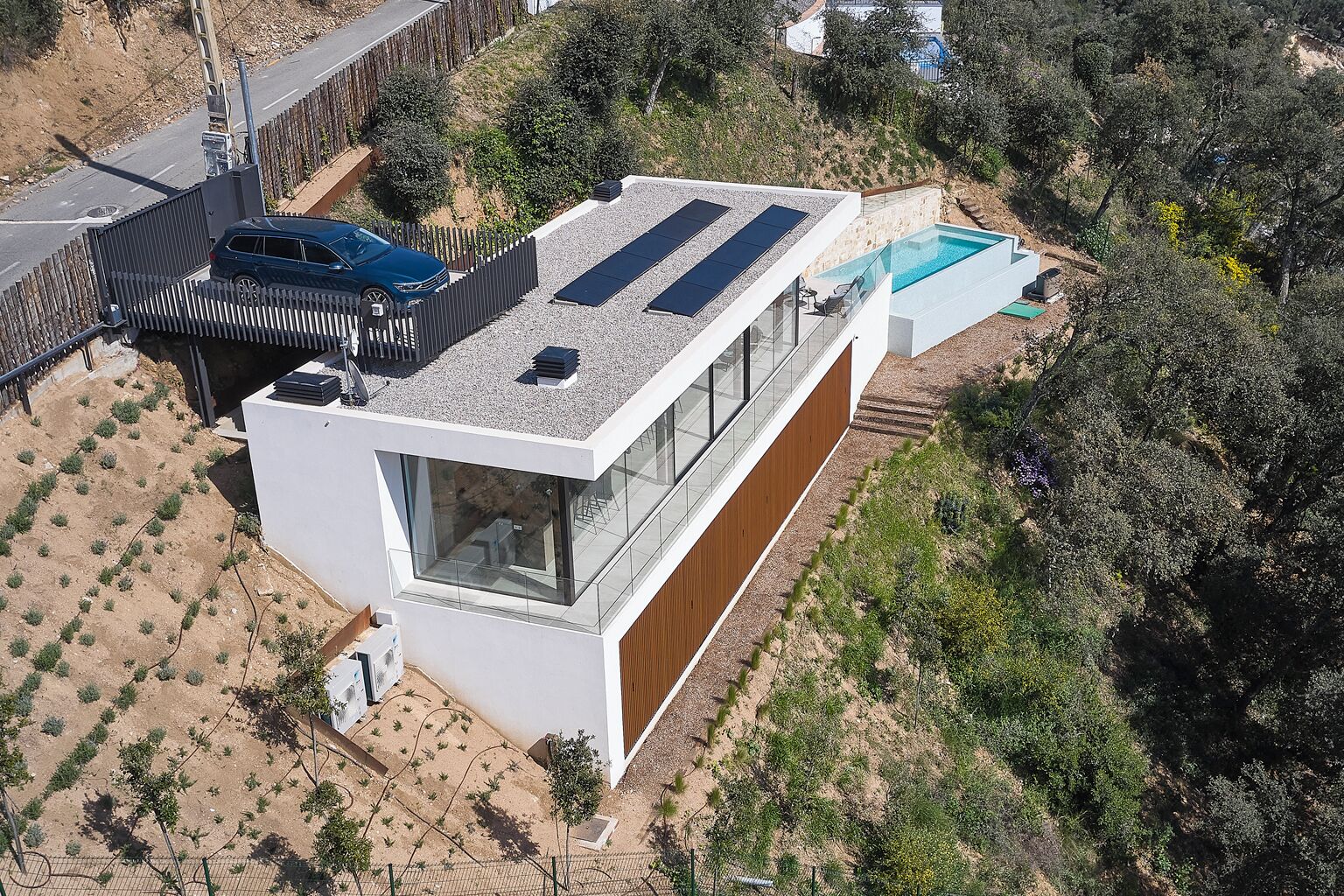A modern house with a large glass window, a swimming pool, and solar panels on the roof.