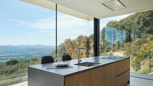 Een moderne keuken met een groot schiereiland, een spoelbak en uitzicht op het buitengebied.