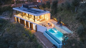Een modern huis met twee verdiepingen, een grote glazen gevel, een terras en een zwembad.