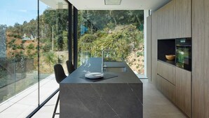 Een moderne keuken met een groot eiland, een eethoek en uitzicht op een heuvel.