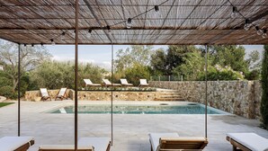 A pool area with lounge chairs and a stone wall. - Mas del Suro -  Masia in the heart of Costa Brava (Mont-ras)