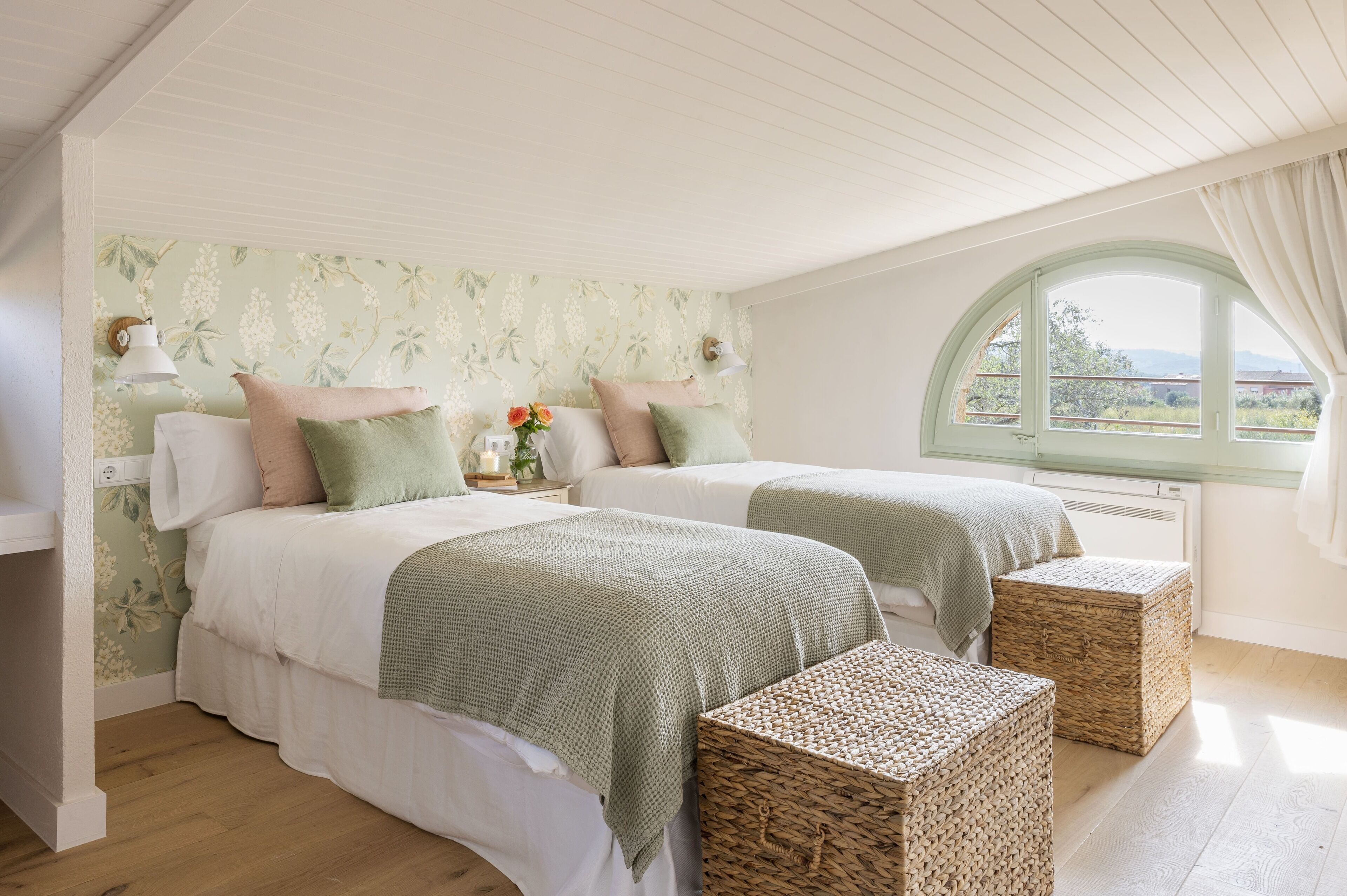 Un dormitorio con dos camas, una ventana con vistas y cestas de mimbre.