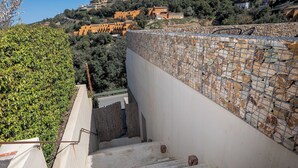 Un escalier en béton mène à un mur de pierre surmonté d’une clôture en métal.