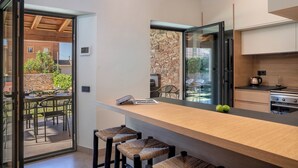 Une cuisine moderne dotée d’un plan de travail en bois, d’un four encastré et d’un mur de pierre en guise de crédence.