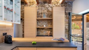 Une cuisine moderne avec des meubles en bois, un mur en pierre et une porte en verre donnant sur un espace extérieur.
