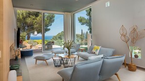 Ein modernes Wohnzimmer mit großem Fenster, bequemer Sitzgelegenheit und Blick ins Freie.