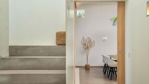 Eine Treppe führt zu einem Essbereich mit einem Tisch und Stühlen, einer Zimmerpflanze und einem kleinen Fenster.