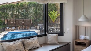 Ein Zimmer mit großem Fenster und Blick auf Pool und Sitzgelegenheiten im Freien.