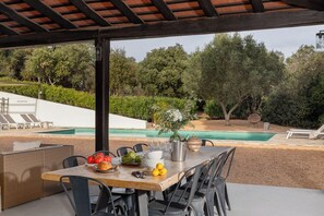 An outdoor dining area with a table set for two, a pool, and a covered seating area. - Casa La Capella - Lovely property with pool in Costa Brava (Girona)