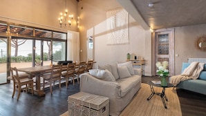 A spacious living area with a wooden dining table, beige sofa, and a small side table. - Casa La Capella - Lovely property with pool in Costa Brava (Girona)