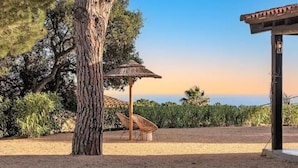 A tree, a thatched umbrella, and a pergola in a landscaped area. - Casa La Capella - Lovely property with pool in Costa Brava (Girona)