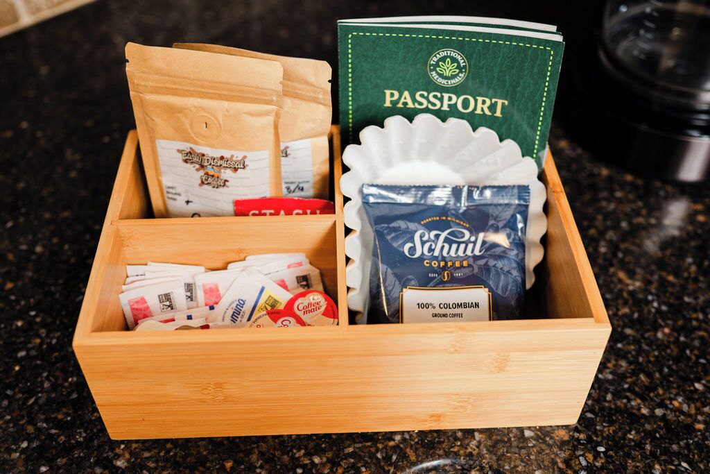 A wooden box containing coffee packets, a passport, and a coffee bag.
