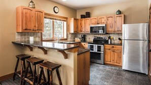 Una cocina con armarios de madera, un refrigerador de acero inoxidable, un microondas y un ventanal grande.