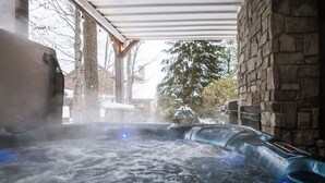 Un jacuzzi con pared de piedra y zona cubierta.