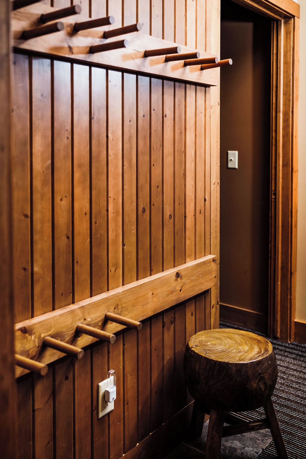 A wooden wall with a built-in shelf and a small stool.