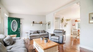 A living room with a green door, grey sofas, a wooden coffee table, and a grey armchair. - G's: Pet friendly: Firepit: King bed: Walk2town (Boyne City)
