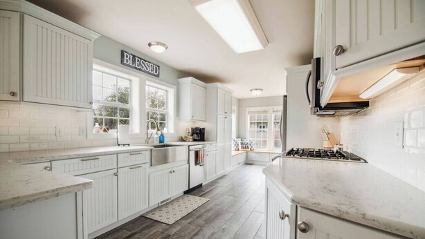 A spacious kitchen with white cabinetry, a large window, and a 'Blessed' sign. - G's: Pet friendly: Firepit: King bed: Walk2town (Boyne City)
