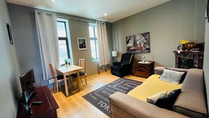 Un salon moderne comprenant un canapé, une table à manger avec des chaises, un téléviseur et une cheminée.