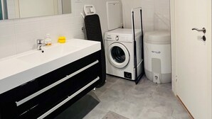Une salle de bain moderne avec un meuble-lavabo blanc, un lave-linge et des toilettes.