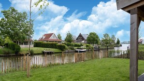 Une vue sur la rivière, avec des maisons, une clôture en bois et un bateau amarré au bord de l’eau.