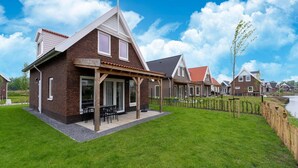 Une maison moderne dotée d’un patio, d’une façade en briques et offrant une vue sur un canal.