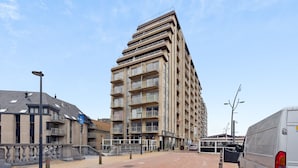 Un hôtel à plusieurs étages doté de balcons, d’un parking et d’un lampadaire.