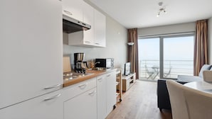 Une cuisine moderne avec des meubles blancs, une machine à café et un petit coin repas offrant une vue sur le balcon.