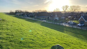 A rural landscape with houses, a fence, and parked cars.