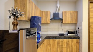 Une cuisine avec des meubles de rangement en bois, un réfrigérateur en acier inoxydable, un four à micro-ondes et un vase rempli de fleurs posé sur le plan de travail.