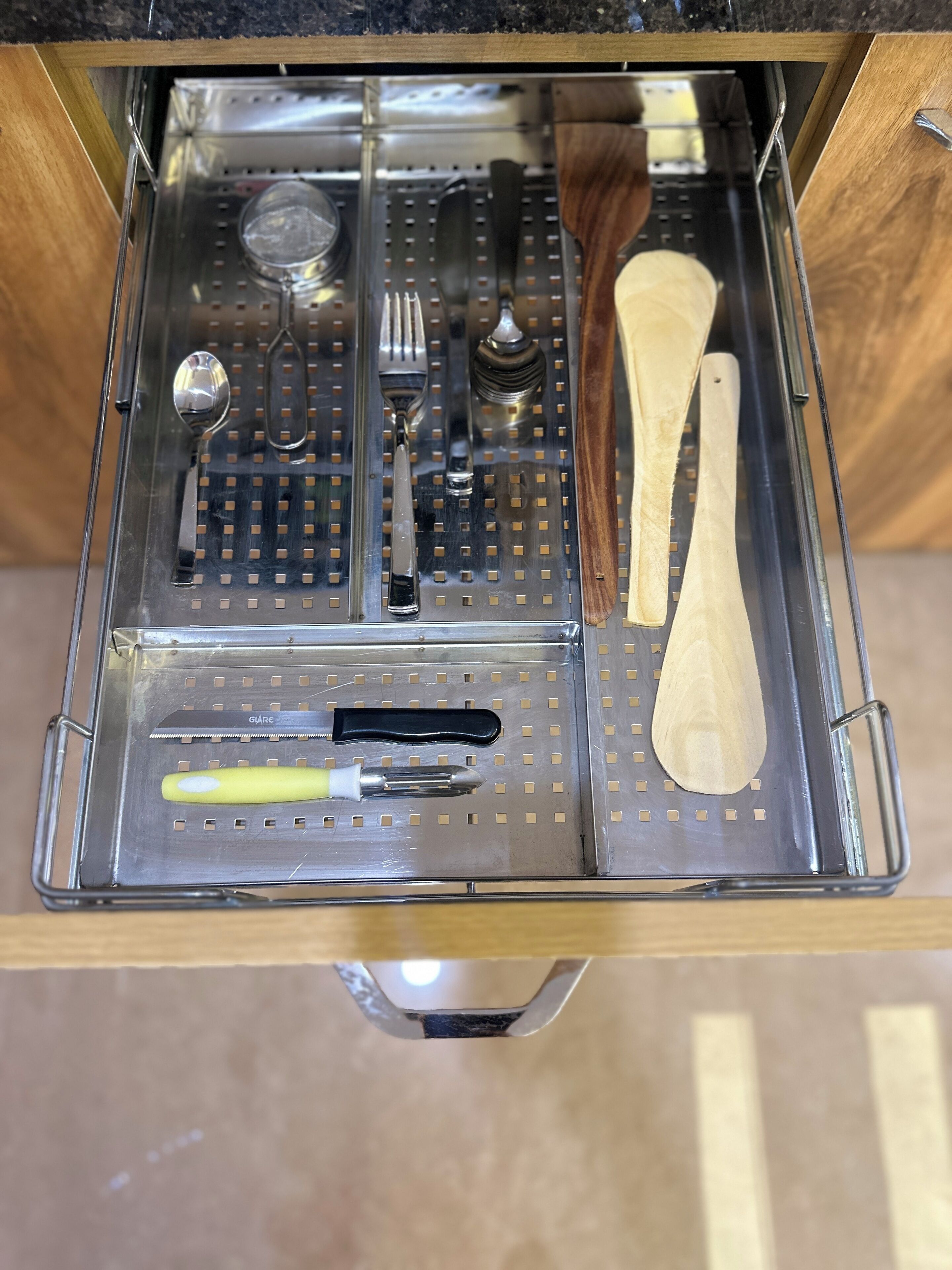 A kitchen drawer with utensils and cookware organized in a drawer organizer.
