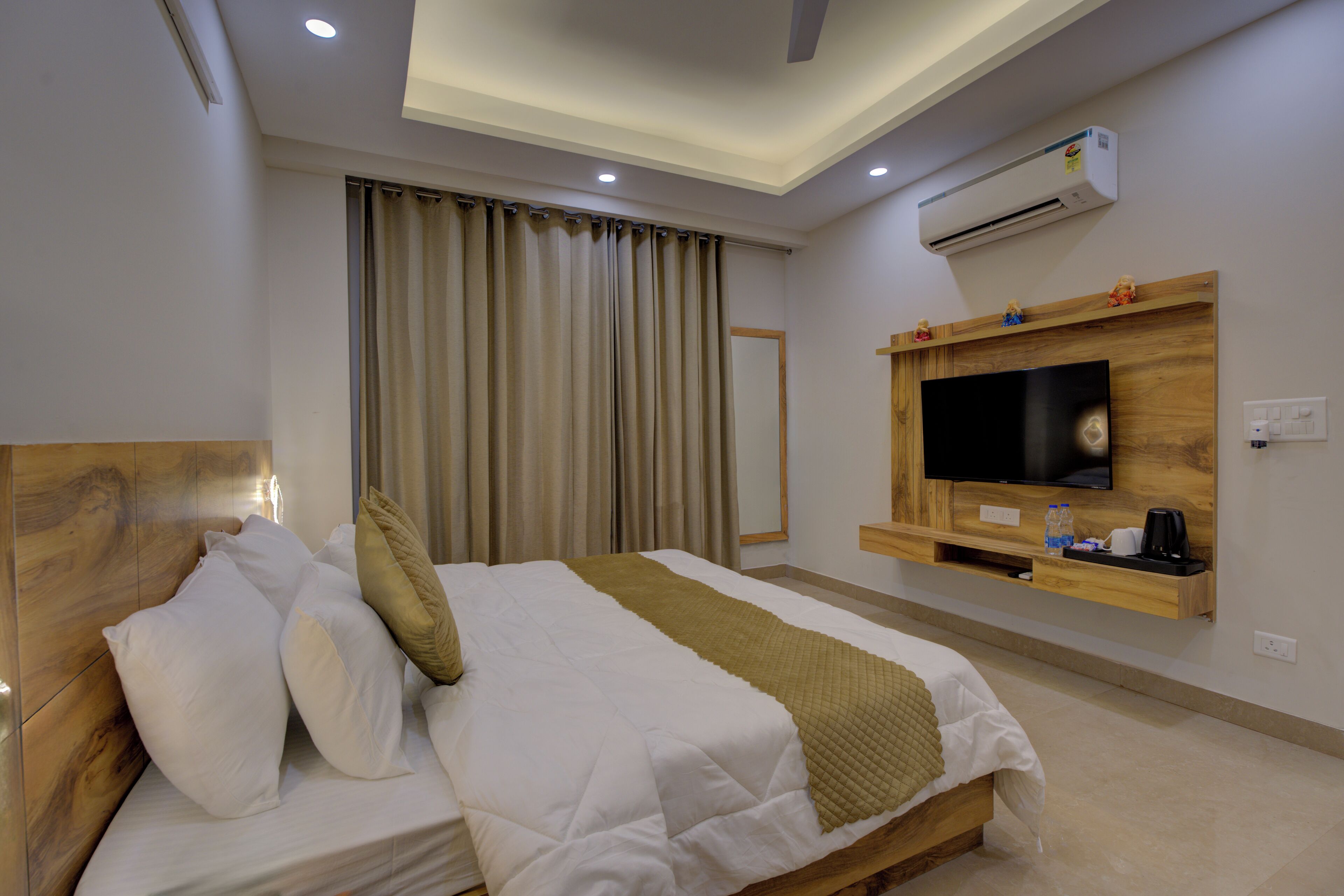 A hotel room with a bed, a TV, an air conditioning unit, and a wooden headboard.