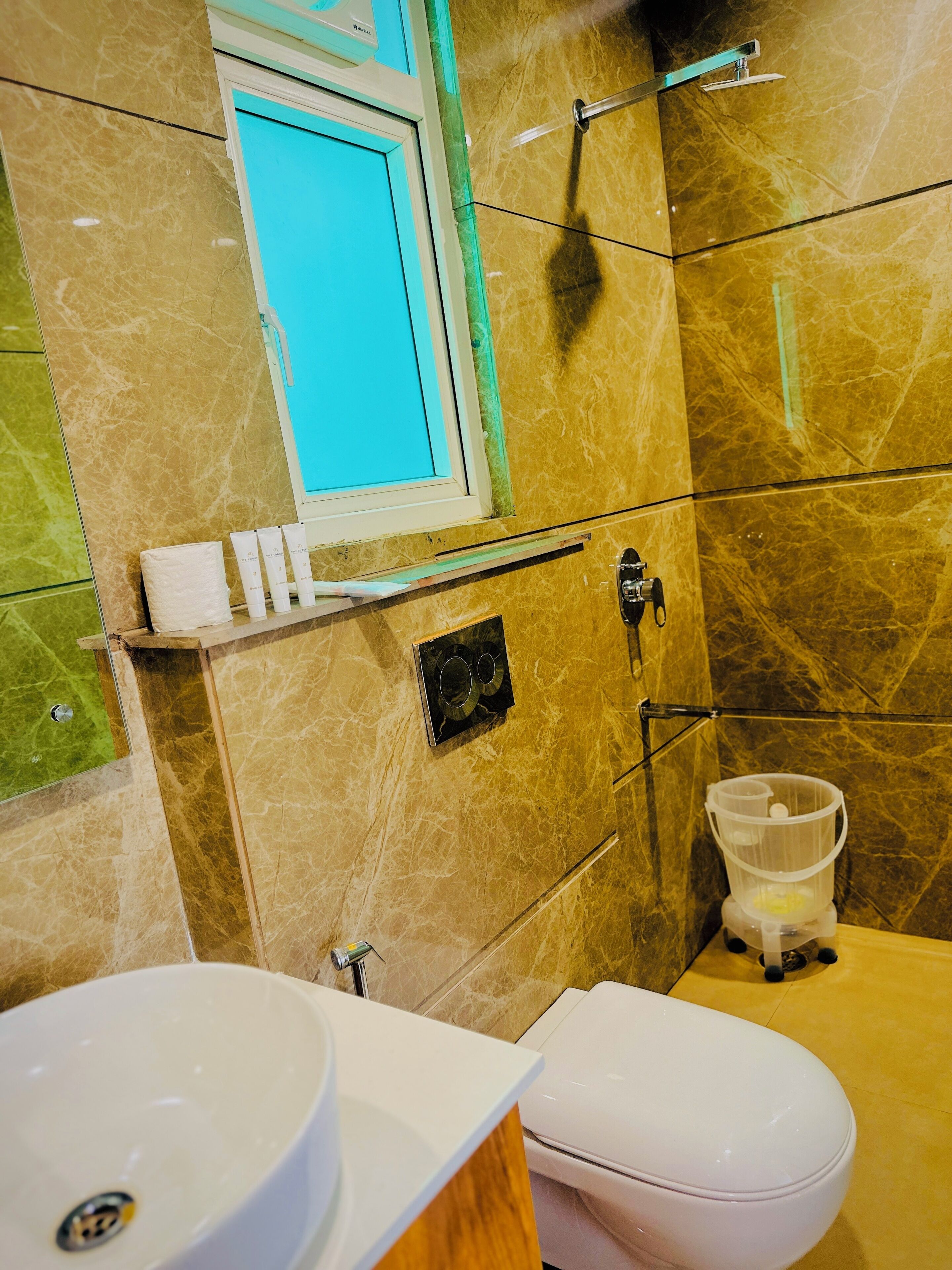 Un baño con piso de mármol, un lavamanos blanco, un inodoro y una zona de ducha.