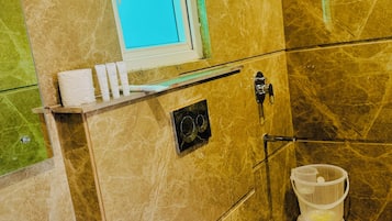 Un baño con piso de mármol, un lavamanos blanco, un inodoro y una zona de ducha.