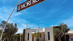 A sign for "LI MORI ROOMS" with a modern building in the background.