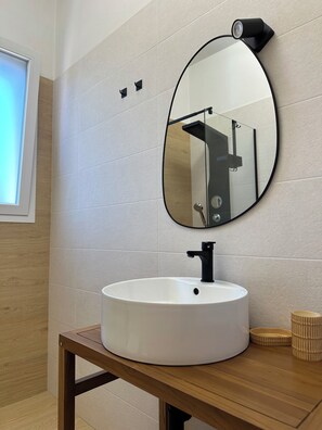 A bathroom with a round mirror, a white sink, and a wooden vanity. - Li Mori Rooms (Lizzanello)