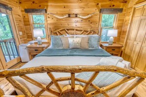 Ein Schlafzimmer in einer Holzhütte mit einem Bett, Nachttischen und einem großen Fenster.