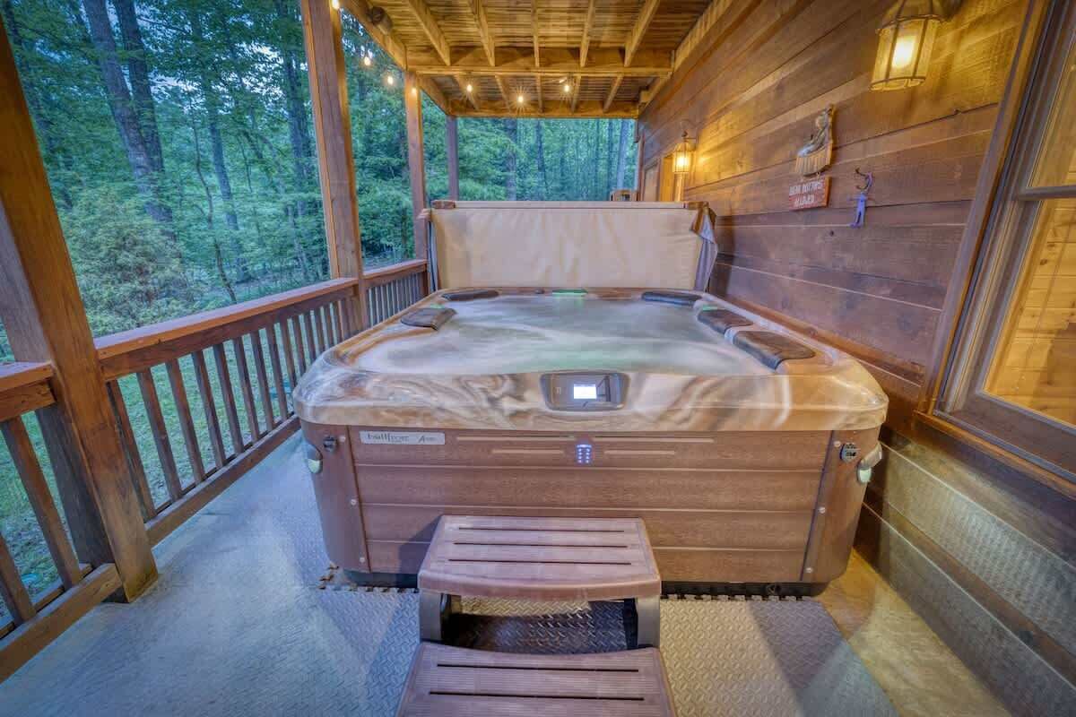 A hot tub in a wooden cabin with a wooden deck and a view of the forest.