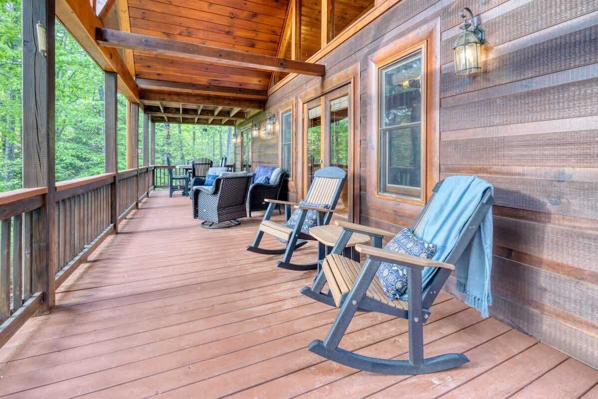 A wooden deck with rocking chairs and a covered area.